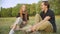 Positive relaxed teenage couple sitting on summer meadow chatting and laughing. Portrait of happy carefree Caucasian