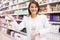 Positive salesgirl helping to choose hair products in cosmetic store