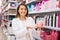 Positive salesgirl helping to choose hair products in cosmetic store