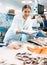 Positive saleswoman demonstrating seabass in fish store