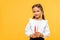 positive schoolkid holding color pencils isolated on orange .