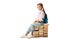 positive schoolkid sitting on books and looking at camera on white.