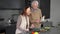 Positive senior man reading recipe talking with woman gathering ingredients for vegan salad. Portrait of Caucasian