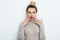 Positive shocked female with attractive look and lips wearing in sweater posing against white wall. Happy woman with hair bun