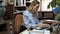 Positive smiling businesswoman sitting at working place in office while working behind laptop