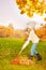 Positive smiling girl with rake cleaning grass