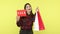 Positive smiling woman holding and showing paper shopping bags and sale signboard