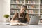 Positive student girl studying in campus library, writing notes