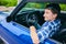 Positive teenage boy sitting in car and smiling