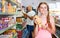 Positive tween girl choosing food products on shopping list in supermarket