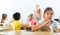 Positive tween schoolgirl sitting at school desk at lesson in class