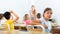 Positive tween schoolgirl sitting at school desk at lesson in class