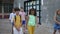 Positive tweenagers walking outside school building on summer day, going to home