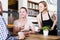 Positive waiter girl brought cup of coffee for couple of different aged people