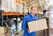 Positive warehouse worker dragging boxes on hands