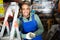 Positive warehouse worker stands next to stepladder and tool shelves in hardware store