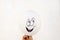 Positive white balloon with a laughing painted face against a li