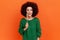 Positive woman with Afro hairstyle wearing green casual style sweater holding multicolored candy in hands, feels hungry, wants to