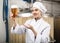 Positive woman brewer presenting glass of fresh beer