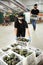 Positive woman in face mask stacking boxes with selected avocado on fruits sorting department