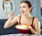 Positive woman keeping diet, eating rice in apartment