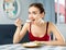 Positive woman keeping diet, eating rice in apartment