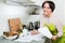 Positive woman signing financial papers in kitchen