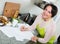 Positive woman signing financial papers in kitchen