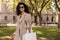 Positive young african woman in sunglasses solo walking in park, looking at camera with smile.