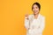 Positive young asian woman in suit point finger up at free space, isolated on yellow studio background