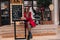 Positive young female model in stylish red outfit resting after walk with cup of tea. Outdoor portrait of pleased