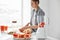 Positive young girl cutting grapefruit blending healthy detox fresh smoothie over white wall.