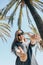 Positive young girl, or a happy tourist on a background of palm trees and blue sky in a hot country