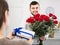 Positive young guy presenting bouquet and gift