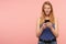 Positive young lovely long haired redhead lady in blue shirt keeping mobile phone in her hands and looking thoughtfully upwards,