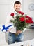 Positive young male presenting bouquet and gift