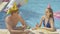Positive young man and woman sitting at poolside with cocktails and talking. Portrait of happy Caucasian boyfriend and