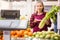 Positive young saleswoman shows fresh greens