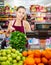 Positive young saleswoman shows fresh greens