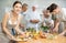 Positive young woman attendee of cooking course decorating meal made of salmon fish