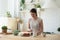 Positive young woman cutting fresh vegetable salad at kitchen