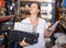 Positive young woman looking construction materials with note list in build store