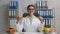 Positive young woman nutritionist showing measuring tape and smiling to camera, sitting at her office