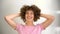 Positive young woman playing with her hands in her curly afro hair