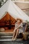 Positive young woman with straw hat poses in background of tent