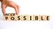 Possible and accessible symbol. Businessman turns wooden cubes and changes the word possible to accessible. Business and possible