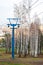 A post with cable cars next to birch trees in the fall.