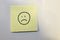 Post-it note with a sad face drawn