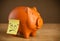 Post-it note with smiley face sticked on piggy bank