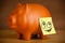 Post-it note with smiley face sticked on piggy bank